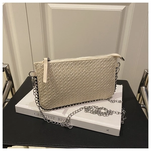 Detail der beige gewebten Umhängetasche mit silberner Kette und Perlenbesatz