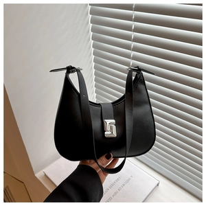 Detail of a minimalist black crescent shoulder bag with a unique silver buckle closure
