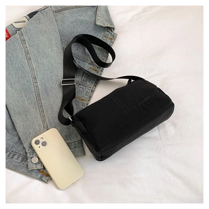 Close-up of lightweight black nylon crossbody bag with adjustable strap and embroidery