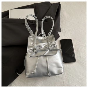 Silver metallic leather mini backpack featuring elegant bow details and drawstring closure
