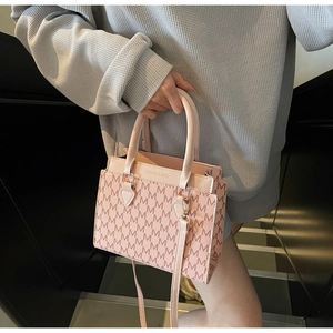 Rosa Umhängetasche mit M-Muster-Monogramm und Rundgriffen präsentiert am Model