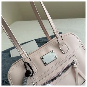 Nahaufnahme der rosa Handtasche aus Kunstleder mit Silberplatte und grauem Anhänger