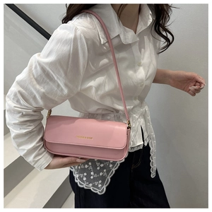 Pink PU leather shoulder bag with golden text detail worn by a model in white
