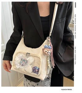 Detail view of cream tote bag with transparent window and anime character badge decor