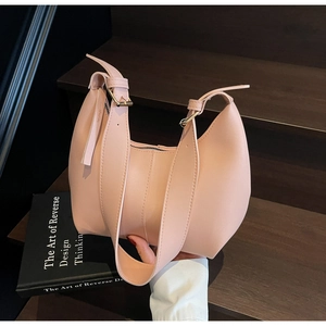 Detail of peach pink crescent shoulder bag featuring premium leather texture and gold hardware