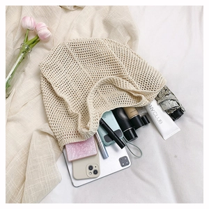 Spacious off-white crochet tote bag filled with everyday essentials on a bed