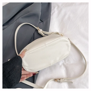 Detail of cream white pebbled leather crossbody bag with golden buckle and adjustable strap