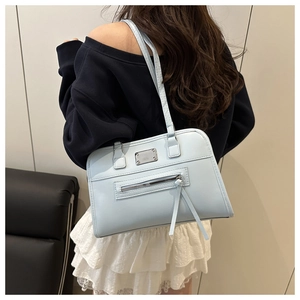 Detailansicht der hellblauen PU-Leder-Schultertasche mit Quasten auf einem Model