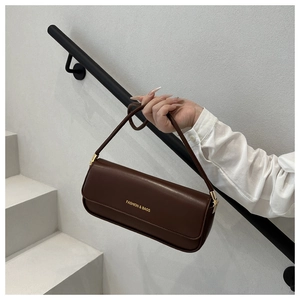 Close-up of a dark brown glossy faux leather baguette bag with gold lettering