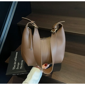 Detail of caramel half-moon tote with wide strap and golden hardware buckle