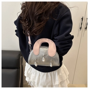 Detail of silver metallic shell bag with pink handle and pearl accents on the front