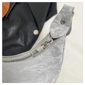 Detailed view of silver crinkled texture fabric and smooth metal zipper on the handbag