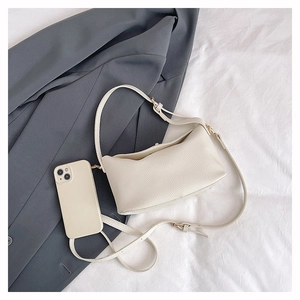 Close-up of white pebble leather bucket bag with dual straps and smartphone for size scale