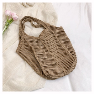 Vue de dessus d'un sac cabas tricoté main kaki sur du lin avec des tulipes roses
