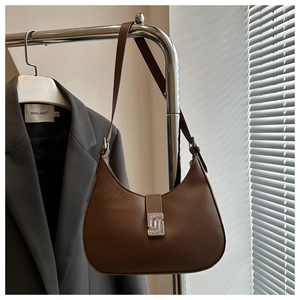 Detail of a brown crescent shoulder bag featuring a geometric silver metallic buckle closure