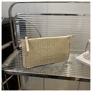 Detail der beigen geflochtenen Clutch mit silbernen Metallperlen und feiner Kette