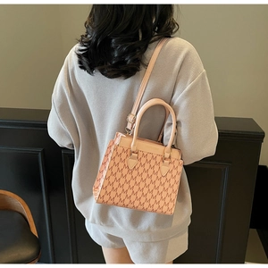 Detail of pink vintage crossbody bag with M-letter print and fashion metal logo plate