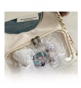 Detail of cream ita bag featuring transparent window with anime badge and lace