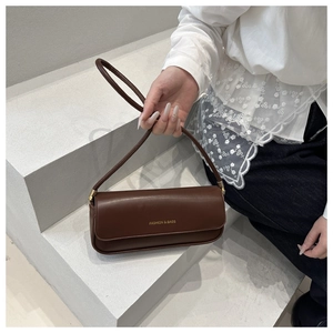 Detail of a dark brown minimalist baguette bag with gold metal buckle and fashion logo