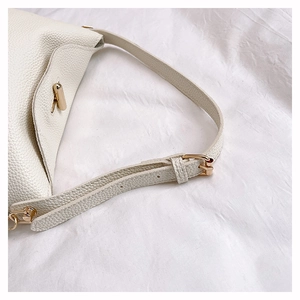 Close-up of cream white lychee leather texture with gold turn-lock and fine stitching