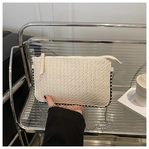 Detail der cremefarbenen geflochtenen Tasche mit Silberperlen und Metallkette