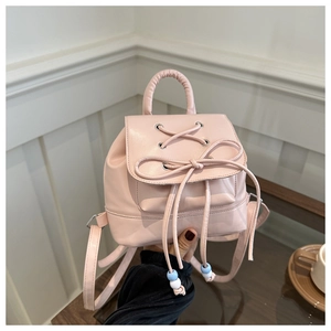 Detail of light pink mini backpack featuring decorative bow and silver eyelets