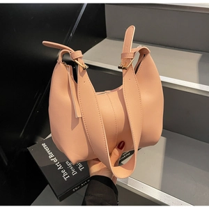 Detail of pink hobo tote bag showing leather texture and gold hardware on stairs