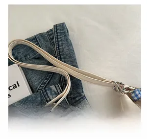 Detail view of cream white PU leather tote with fine shoulder strap and metal buckle