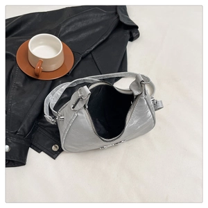 Detail shot of silver metallic crescent bag showing silver zipper and black fabric lining