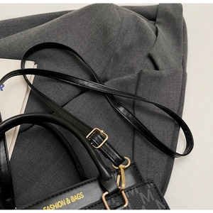 Detailaufnahme der schwarzen Handtasche mit Goldbeschlägen und gelbem Logo-Aufdruck