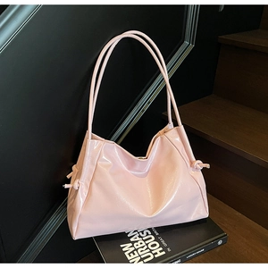 Close-up of pink patent leather tote bag with decorative side knots and glossy finish