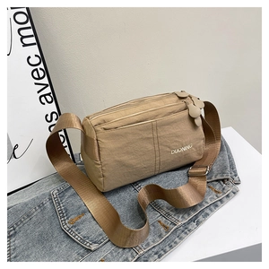 Detailed view of khaki nylon crossbody bag with flower zipper and adjustable strap