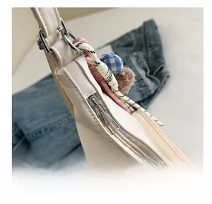 Detailed close-up of the smooth metal zipper and decorative tassels on the beige tote bag