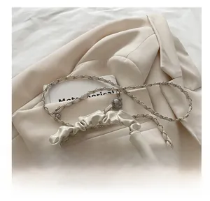 Close-up of white cloud bag featuring pleated handle, metal chain and pearl accents