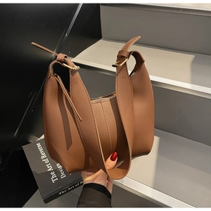 Close-up of brown matte leather hobo bag with wide shoulder strap and gold buckle detail