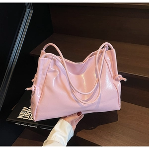 Detailed close-up of pink patent leather tote bag with knot detail and glossy finish