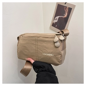 Detail of light khaki nylon crossbody bag with embroidery and smooth woven shoulder strap