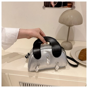 Silver shell bag with broad black handle and pearls on a stylish cafe table setting