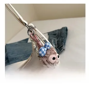 Close-up of a plush purple monkey charm with a checkered bow on a white tote bag