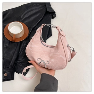 Detail of pink crescent bag with silver bow buckle and marble texture on black leather