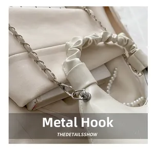 Detail of cream white cloud shoulder bag featuring hardware hook and pearl strap accents