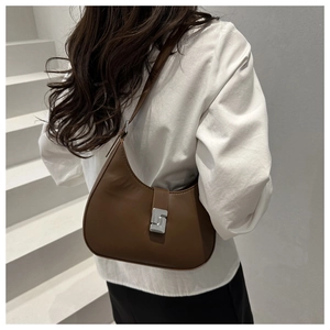 Close-up of minimalist brown crescent underarm bag with silver metal buckle on model