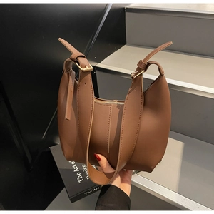Detail view of brown leather tote bag with adjustable buckle strap on modern steps