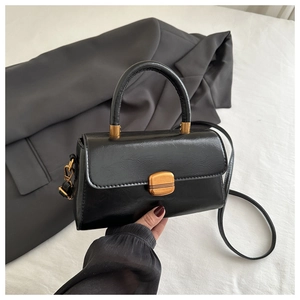 Detail of black glossy vintage handbag with gold buckle and micro-pleat leather texture