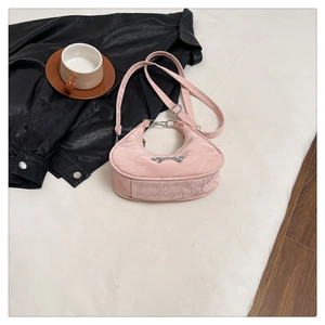 Detail of pink crescent bag featuring silver bow hardware and adjustable shoulder strap