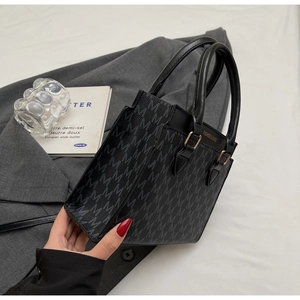 Detail of vintage monogram pattern handbag with golden buckle on a grey suit jacket