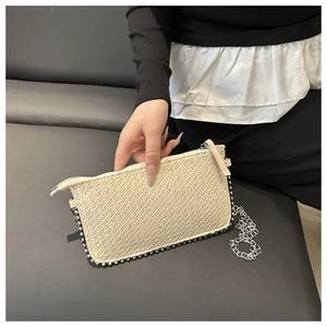 Nahaufnahme der beigen gewebten Tasche mit Silberperlenrand und Metallkettenriemen