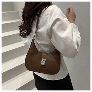 Detail of a brown semi-circle hobo bag featuring a silver geometric buckle on a strap
