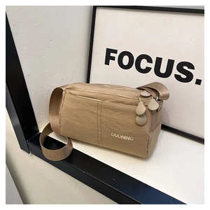 Close-up of khaki nylon crossbody bag with multi-layer zippers and embroidered logo