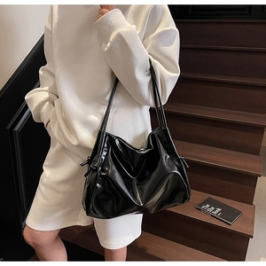 Detail of glossy black tote bag with shoulder straps and decorative side drawstrings
